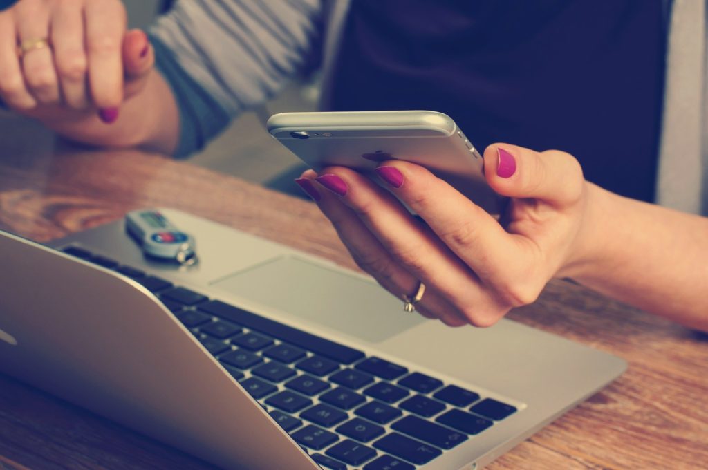 Mujer utilizando su smartphone y su ordenador portátil