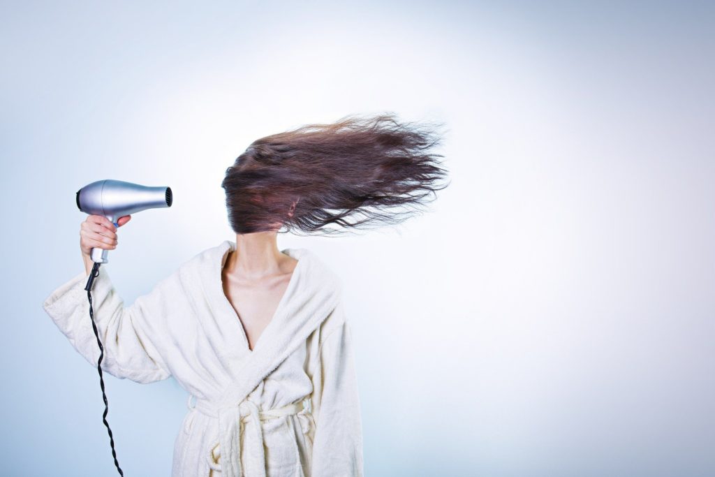 Mujer con el pelo cubriéndole la cara a causa del aire del secador