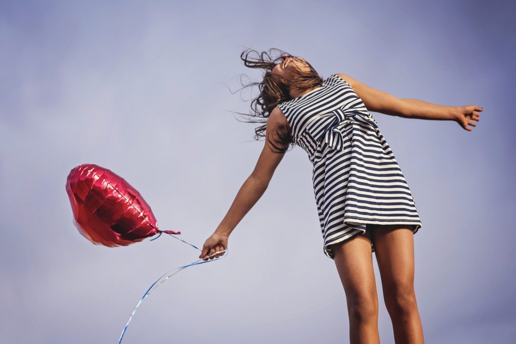 Chica feliz y emocionada con un globo en la mano.